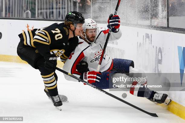 Jesper Boqvist of the Boston Bruins upends Joel Edmundson of the Washington Capitals going for a loose puck during the first period at TD Garden on...