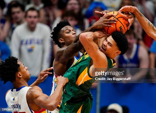 RayJ Dennis of the Baylor Bears fights for a loose ball against K.J. Adams Jr. #24 and Elmarko Jackson of the Kansas Jayhawks during the first half...