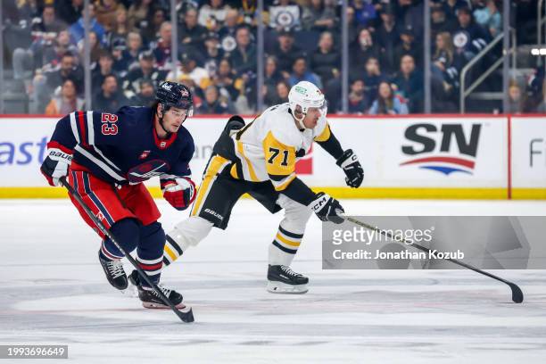 Sean Monahan of the Winnipeg Jets and Evgeni Malkin of the Pittsburgh Penguins follow the play down the ice during first period action at the Canada...