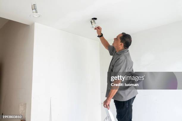 electrician fixing ceiling lamp wiring - lampje-vervangen stockfoto's en -beelden