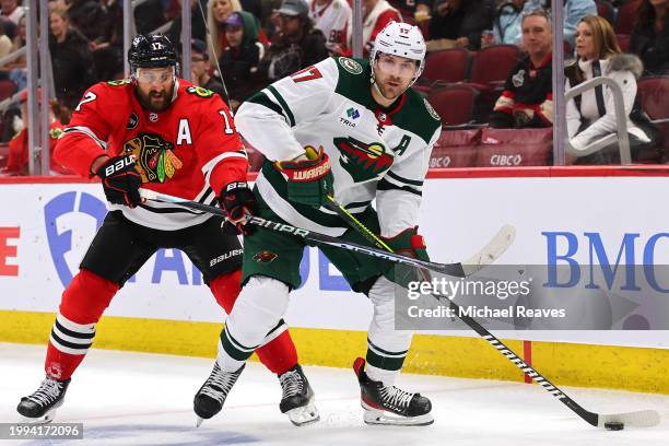Nick Foligno of the Chicago Blackhawks and Marcus Foligno of the Minnesota Wild battle for control of the puck during the second period at the United...