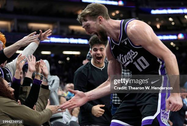 Domantas Sabonis of the Sacramento Kings celebrates with fans after making a three-point shot at the buzzer to end the third quarter against the...