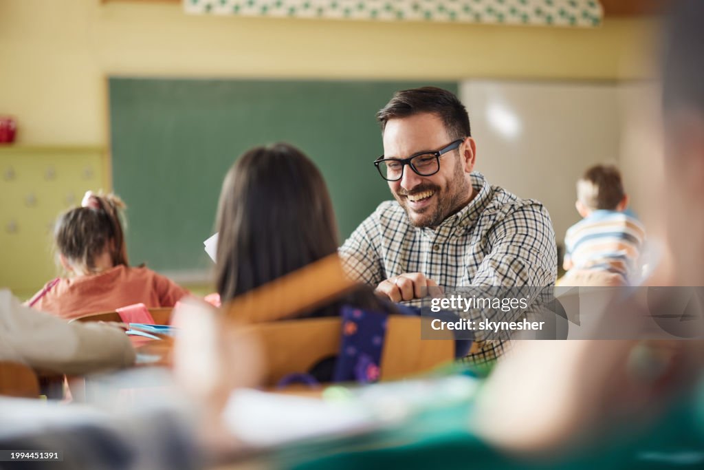 Happy professor assisting his elementary students on a class at school.