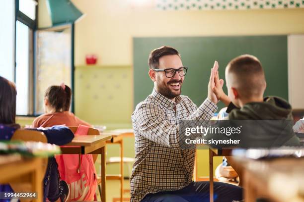 insegnante felice e scolaro che si danno l'un l'altro high-five in una classe. - insegnare foto e immagini stock