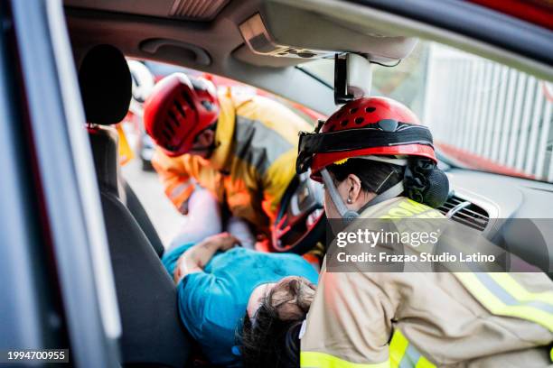 feuerwehrleute helfen einem autounfallopfer - autounfall stock-fotos und bilder