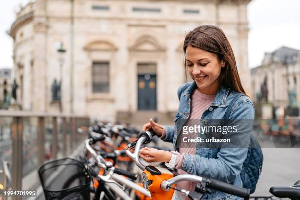young woman renting an electric bike using smart watch in copenhagen in denmark - royalty payment stock pictures, royalty-free photos & images