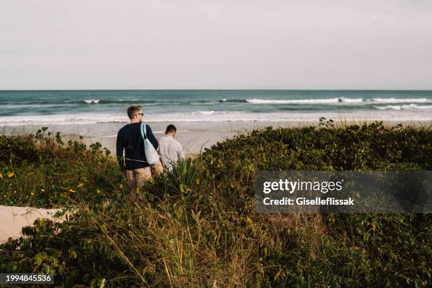 young gay couple walking along a scenic path to the the ocean - couple dunes stockfoto's en -beelden