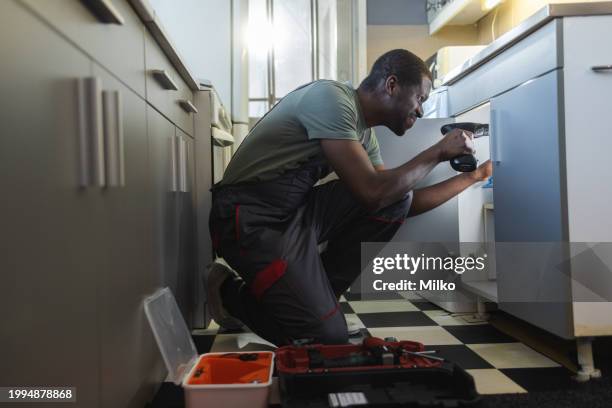 the plumber fixing the sink in the kitchen - under sink stock pictures, royalty-free photos & images