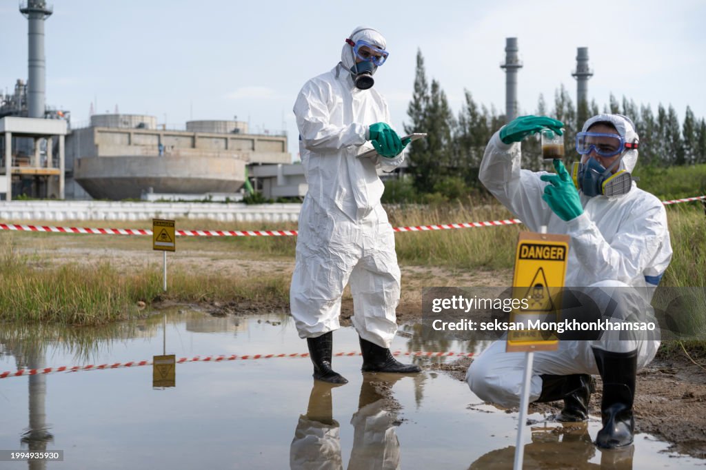 Environmental researcher taking water sample from toxic on oil spill mixed with water.