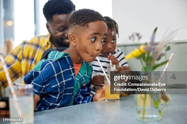 young boy enjoying drink in cafe with family - striped straw stock pictures, royalty-free photos & images