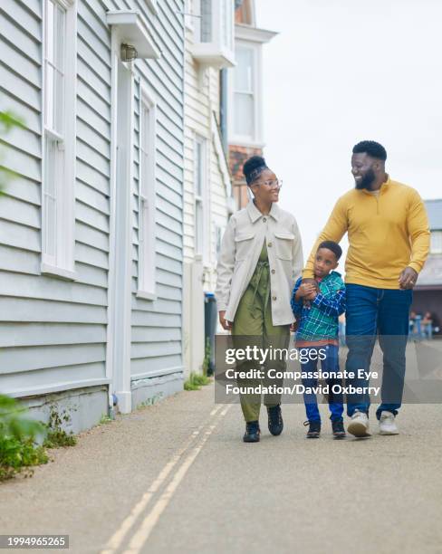 wide shot of family enjoying walk in seaside town - single father stock pictures, royalty-free photos & images