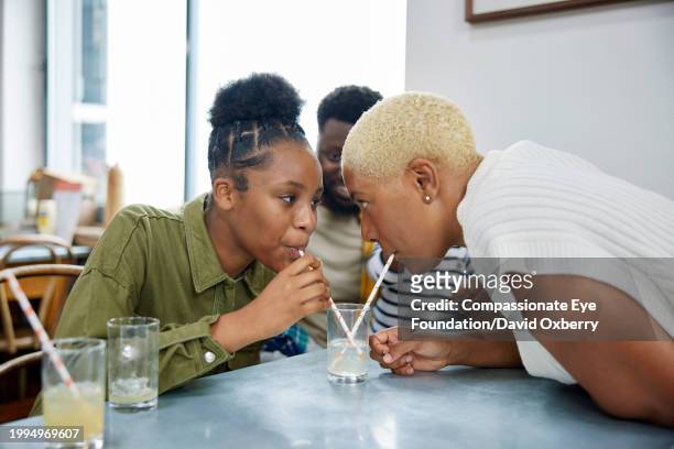 medium shot of mother and teenage daughter having a drinking race in cafe on weekend break - championship day two stock pictures, royalty-free photos & images