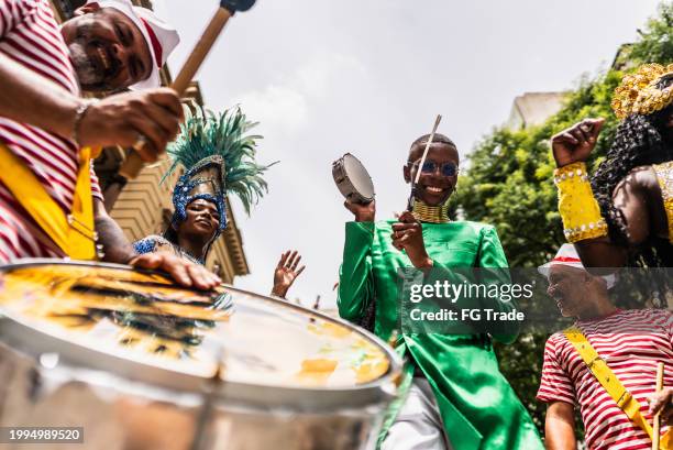 portrait of a young man playing tambourine at a street carnival party - carnaval rio stock pictures, royalty-free photos & images