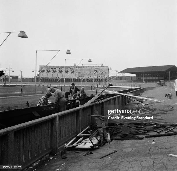 Group of people carry out repairs to the barrier at Harringay Stadium, the greyhound racing and motorcycle speedway venue, London, June 27th 1957.