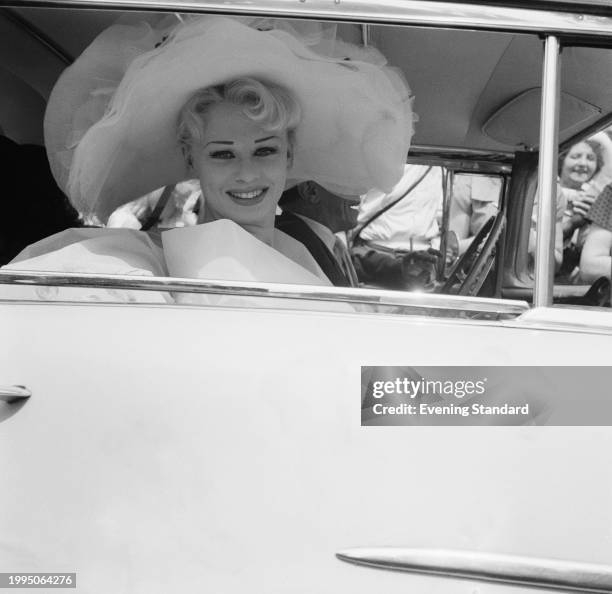 Model and actress Sabrina wears a large hat while smiling from inside a car at Royal Ascot, Berkshire, June 18th 1957. Sabrina had gate crashed the...