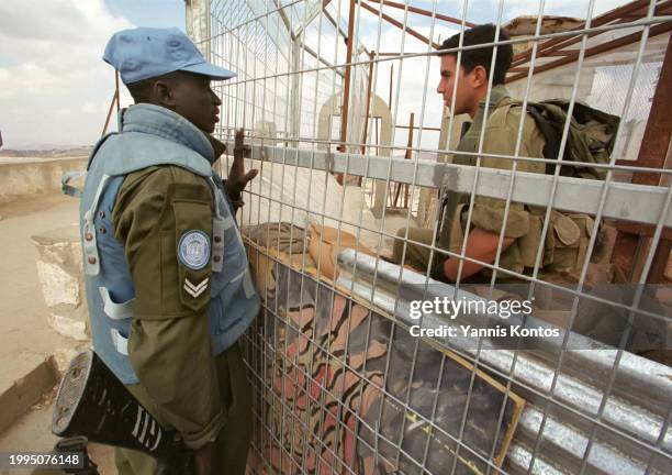 An Israeli soldier, right, and a UN peace keeper chat at the fence dividing the Sheik Abbad tomb between the Lebanese and Israeli sides near the...