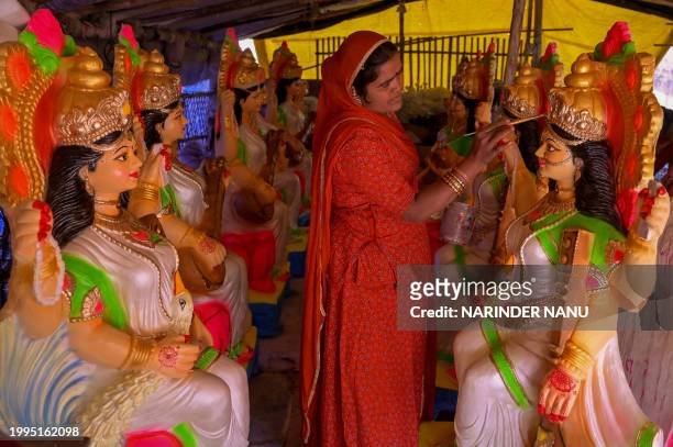 An artist gives final touches to idols of Hindu Goddess Saraswati, ahead of Saraswati Puja, at a workshop in Amritsar on February 11, 2024.