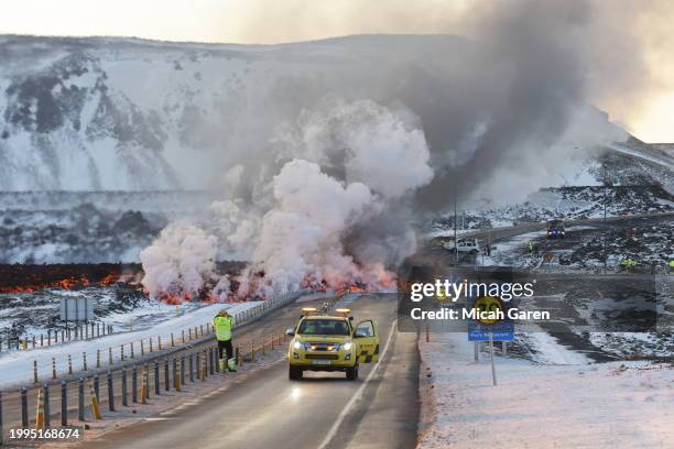 Emergency services close a road as lava erupts from a fissure on February 8, 2024 in Grandavik, Iceland. A volcanic fissure opened north of Grindavik...