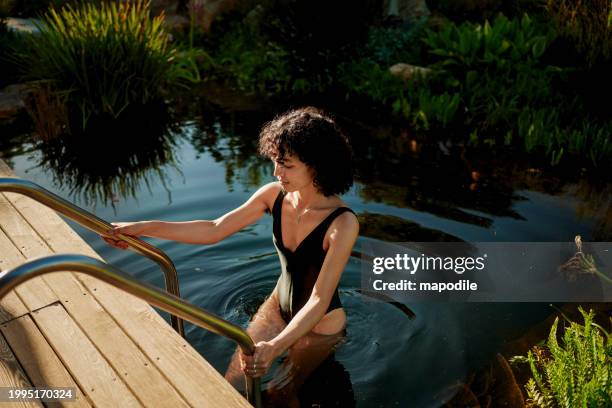young woman climbing out of the natural swimming pool of a wellness retreat - spa bildbanksfoton och bilder