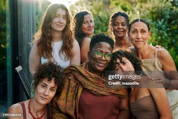 smiling group of diverse women sitting on a patio during a wellness retreat - alleen vrouwen stockfoto's en -beelden