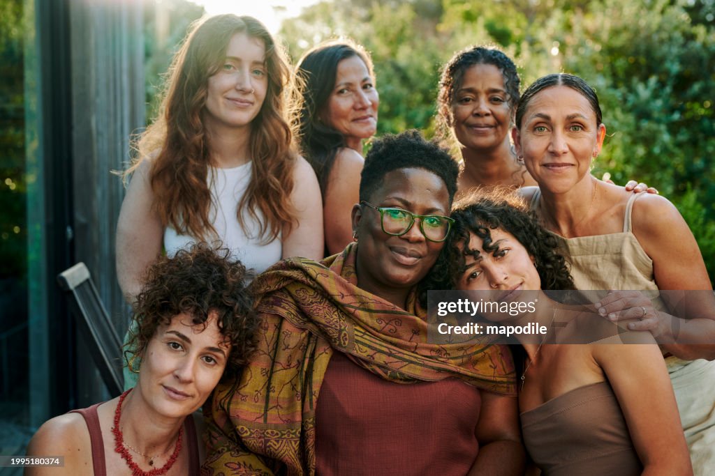 Grupo sorridente de mulheres diversas sentadas em um pátio durante um retiro de bem-estar