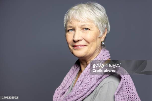 beautiful senior woman looking happy against grey background - scarf stock pictures, royalty-free photos & images