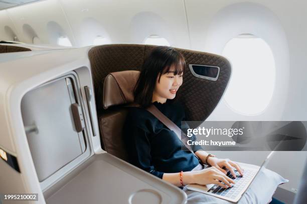 joven empresaria asiática trabajando en el avión - viaje de negocios fotografías e imágenes de stock