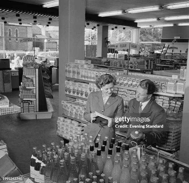 Man and woman look at a label between aisles inside a Premier Supermarkets store, Britain, July 25th 1957. Premier Supermarkets had a chain of 11...