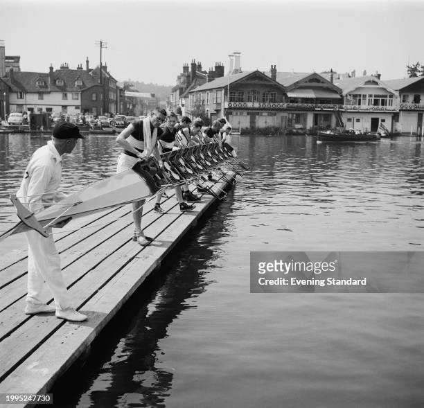 Rowing team lift their scull boat on a jetty at the Henley Royal Regatta, Henley-on-Thames, July 17th 1957.