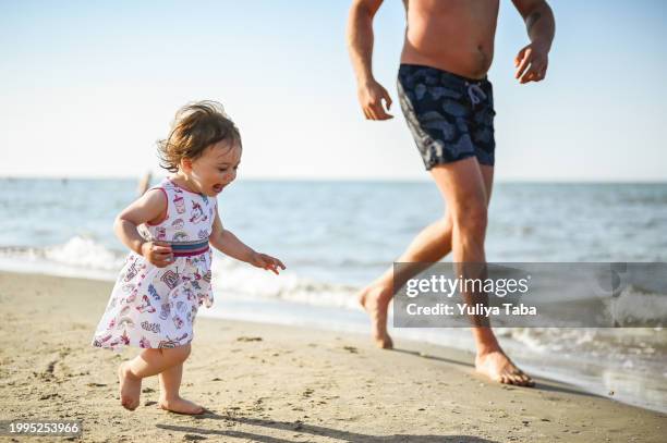 candid family on a beach. - baby girl stock pictures, royalty-free photos & images