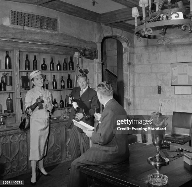 Retail clerk shows customers wines at Fortnum & Mason department store, Piccadilly, London, July 8th 1957.