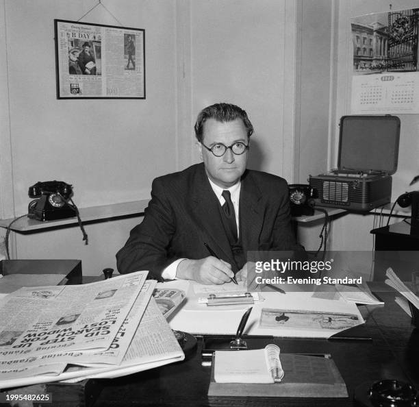 Evening Standard newspaper editor, Percy Elland writing at his desk, Shoe Lane, London, May 7th 1957.