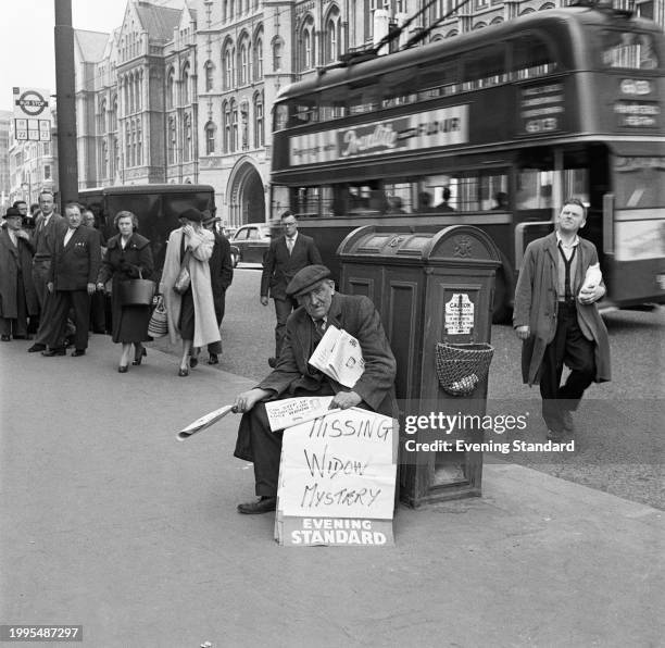 An Evening Standard newspaper vendor sits on a pavement in central London as pedestrians and a Routemaster bus move past, May 7th 1957. The headline...