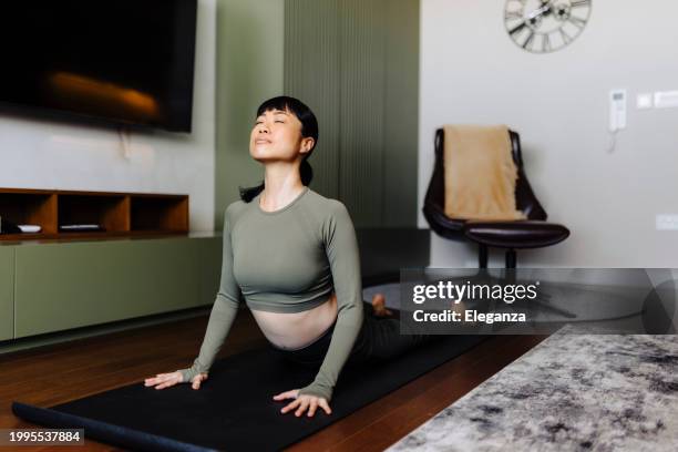 portrait of gorgeous young woman practicing yoga indoor. beautiful girl practice cobra asana in class. calmness and relax, female happiness. - cobra stock pictures, royalty-free photos & images