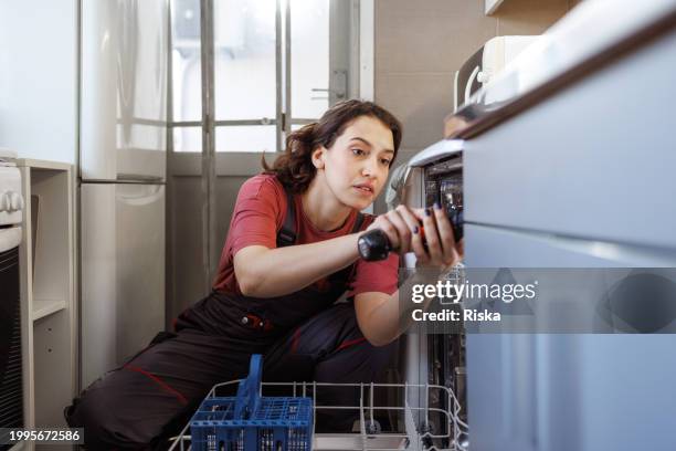 a handywoman installing the dishwasher - handywoman stock pictures, royalty-free photos & images