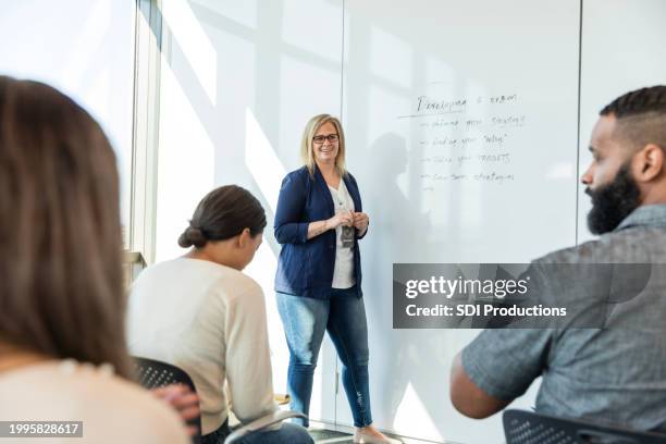 female manager leads employee engagement meeting in conference room - colleague engagement stock pictures, royalty-free photos & images