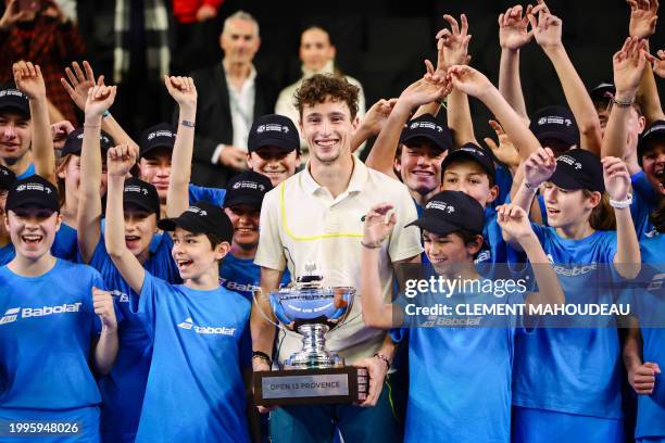 France's Ugo Humbert holds his trophy as he poses with ball kids after winning the ATP Open 13 final tennis match on February 11, 2024 in Marseille,...