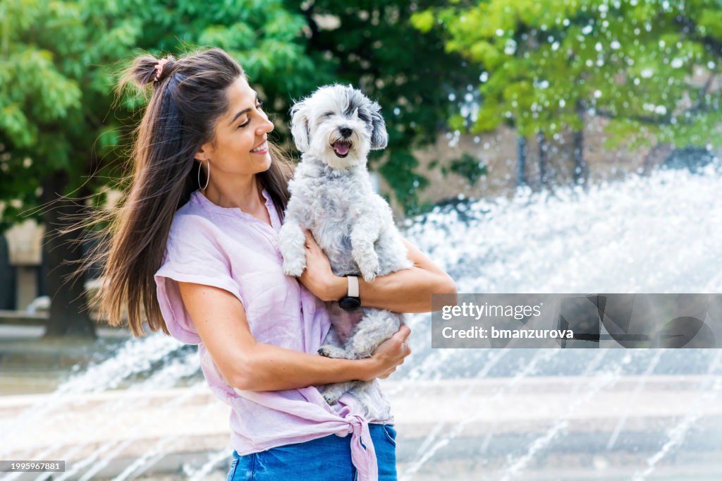 Mujer abrazando a su perro habanero en la calle