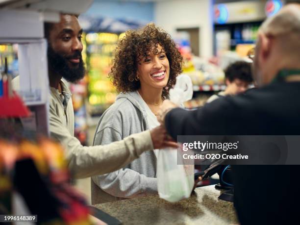 pareja joven de compras en una tienda de conveniencia - tienda del vecindario fotografías e imágenes de stock