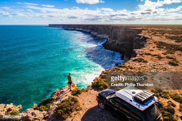 aerial view of car parked with camper and young man overlooking the great australian bight - australian outback landscape stockfoto's en -beelden