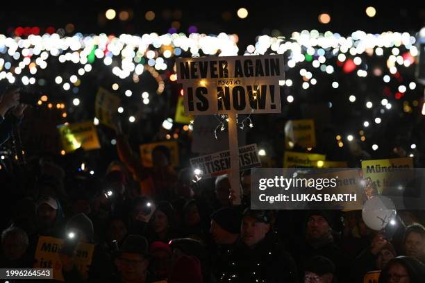 Crowd raises lights and placards reading "Never again is now!" during a demonstration against racism, anti-Semitism and hate speech, named "Sea of...