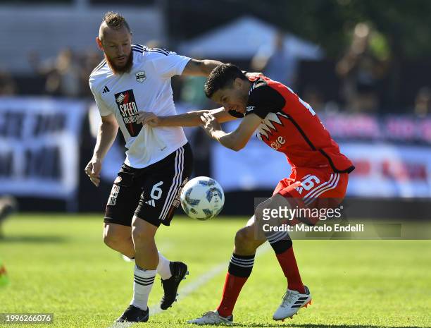 Nicolas Dematei of Deportivo Riestra competes for the ball with Ignacio Fernandez of River Plate during a Copa de la Liga 2024 group A match between...