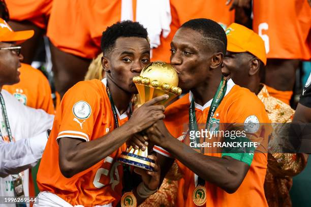 Ivory Coast's forward Max-Alain Gradel and Ivory Coast's forward Simon Adingra kiss the Africa Cup of Nations trophy on the podium after Ivory Coast...