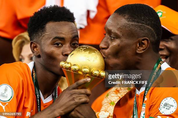 Ivory Coast's forward Max-Alain Gradel and Ivory Coast's forward Simon Adingra kiss the Africa Cup of Nations trophy on the podium after Ivory Coast...