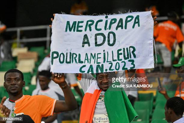 An Ivorian supporter holds a banner reading "Thank dad Alassane Ouattara for the best CAN 2023" during the Africa Cup of Nations 2024 final football...