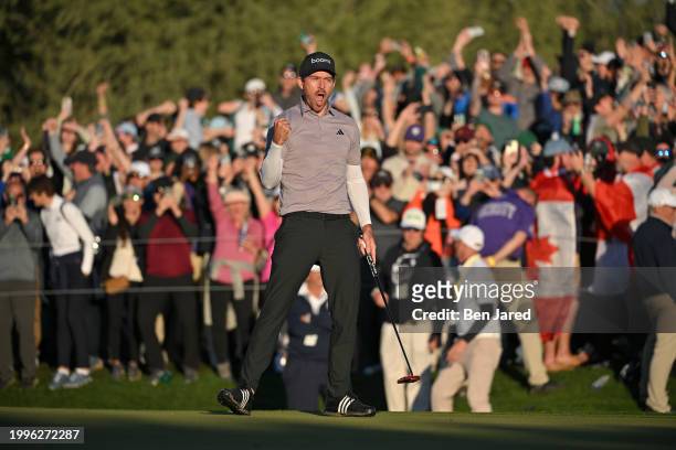 Nick Taylor of Canada fist pumps after making a putt on the 18th green to force a playoff hole during the final round of WM Phoenix Open at TPC...