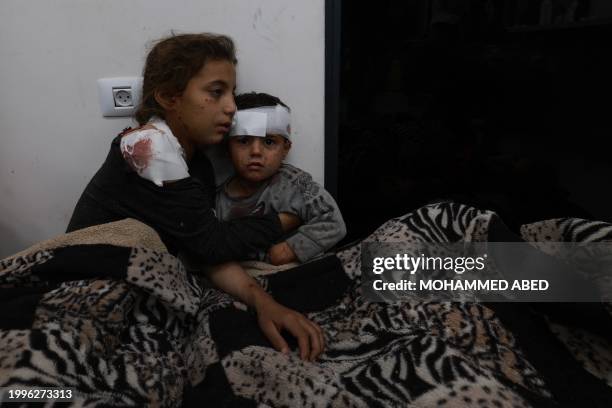 Wounded Palestinian girl Somay al-Najar comforts her brother Yamen following Israeli bombardments over Rafah in the southern Gaza Strip on February...