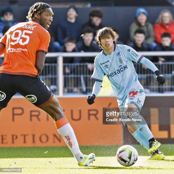 Reims' Junya Ito is seen in action with Lorient's Isaak Toure in a Ligue 1 football match on Feb. 11 in Lorient, France.
