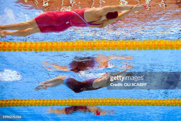 Claire Curzan and Britain's Lauren Cox compete in a heat of the women's 100m backstroke swimming event during the 2024 World Aquatics Championships...