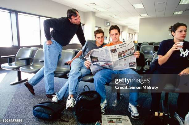 Bruce Arena -USA Mens soccer coach- reading the paper with players Ante Razov and Josh Wolff whilst waiting for a flight on October 13, 2000 in...